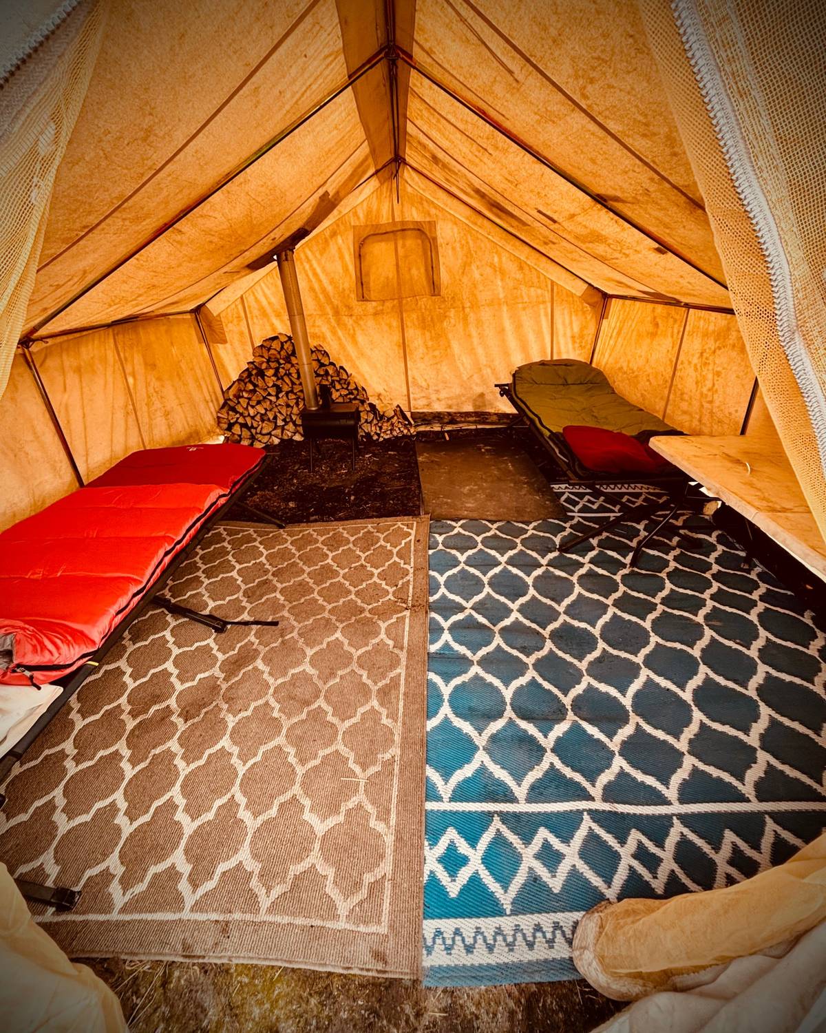 Inside a heated wall tent with cots and wood stove