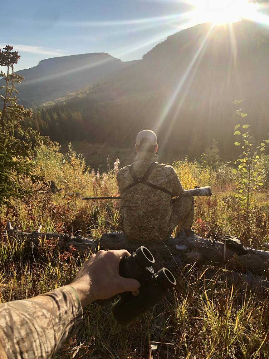 Hunter glassing at sunrise in the Alberta mountains