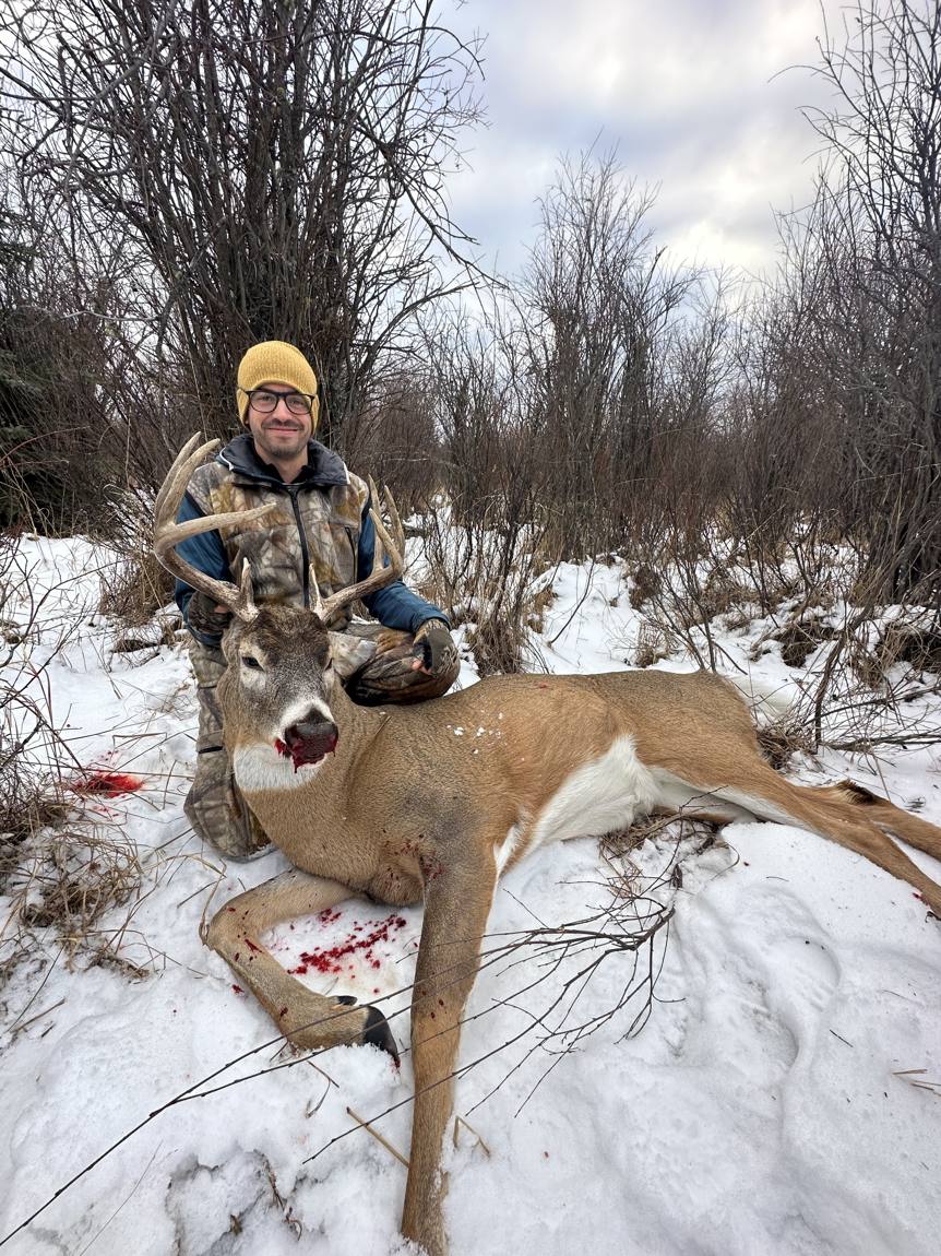 Hunter with an Alberta whitetail buck in the snow